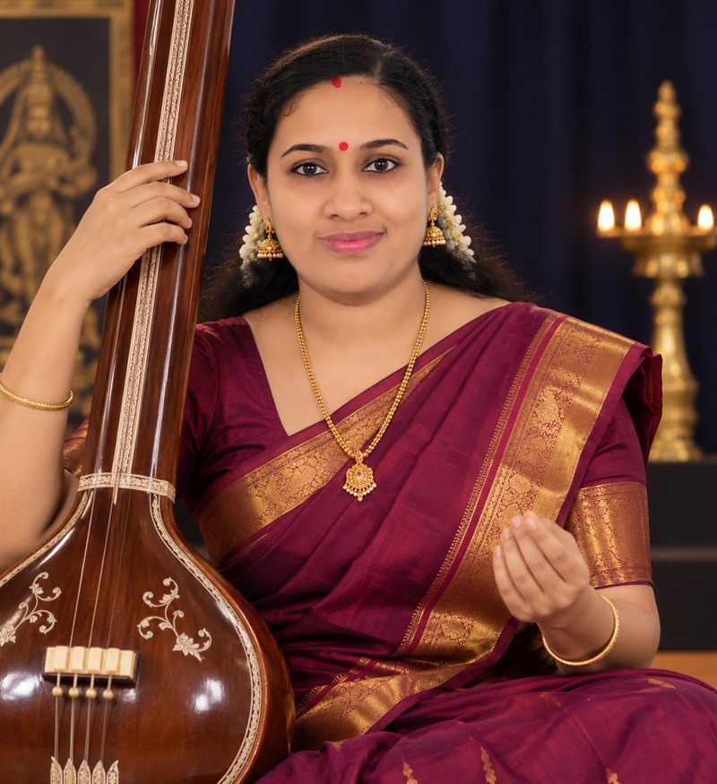 Guru of Swaritham Sadgurukulam seated with a tanpura before a lit nilavilakku